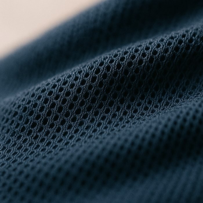 Close-up of matte navy technical performance polyester knit with a fine micro-mesh structure